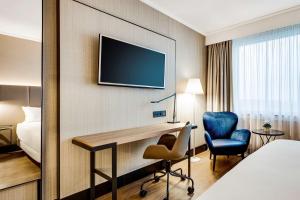 a hotel room with a desk and a tv on a wall at NH Brussels Airport in Diegem
