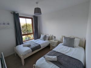two beds in a room with a window at Brooklands Central Apartment in Newcastle