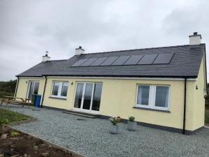 a yellow house with solar panels on the roof at Loch Caroy Bay Cottage in Ose