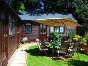 a table and chairs with an umbrella in a yard at Ashleigh Lodge in Hunstanton