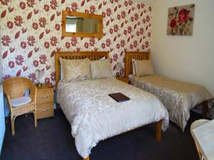 1 Schlafzimmer mit 2 Betten, einem Spiegel und einem Stuhl in der Unterkunft Ashleigh Lodge in Hunstanton