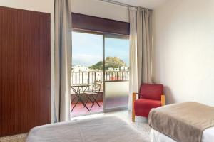 a bedroom with a bed and a red chair and a balcony at Hotel Leuka in Alicante