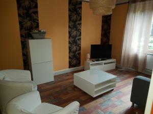 een woonkamer met witte meubels en een televisie bij Gite La maison d'Odette in Saint-Georges-de-Mons