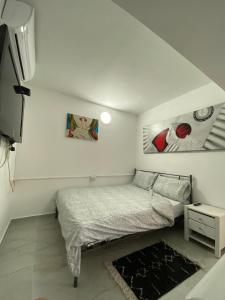 Levis house Eilat في إيلات: غرفة نوم صغيرة بها سرير ولوحات على الحائط