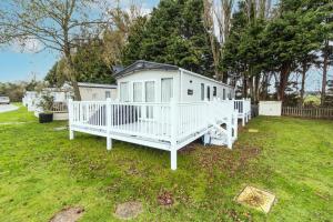 een wit huis in het gras in een tuin bij Lovely 6 Berth Caravan With Wi-fi At Weeley Bridge In Essex Ref 69015r in Weeley