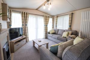 een woonkamer met een bank en een tv bij Lovely 6 Berth Caravan With Wi-fi At Weeley Bridge In Essex Ref 69015r in Weeley