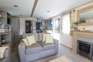 a living room with a couch and a fireplace at Lovely 6 Berth Caravan With Wi-fi At Weeley Bridge In Essex Ref 69015r in Weeley