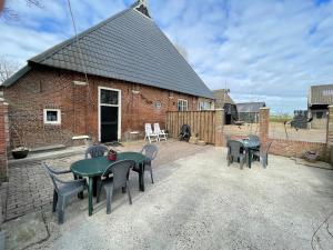 a patio with tables and chairs and a brick building at Appartement met eigen sauna en sport-en spelruimte in Ee