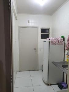 a white kitchen with a refrigerator in a room at Estudio no centro de campinas 26m² in Campinas