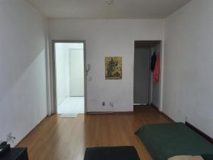 an empty room with a white wall and wooden floors at Estudio no centro de campinas 26m² in Campinas