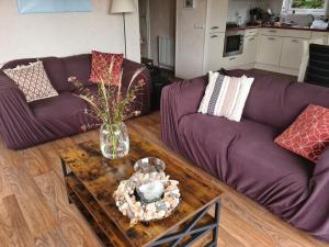 a living room with a purple couch and a table with a vase at Strandhut 64 in Sint Annaland