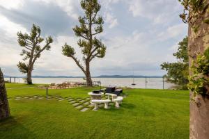 un parco con tavolo, sedie e acqua di Loulou Apartman - Balatonboglár a Balatonboglár