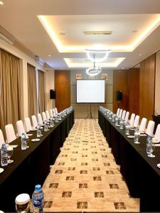 una sala de conferencias con mesas y sillas largas y una pantalla blanca en Grand Papua Hotel Sentani, en Weversdorp