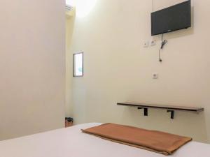 a bedroom with a bed with a flat screen tv on the wall at Hotel Lido 88 Sorong Mitra RedDoorz in Sorong