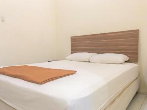 1 cama blanca con cabecero de madera y 2 almohadas en Hotel Lido 88 Sorong Mitra RedDoorz, en Sorong