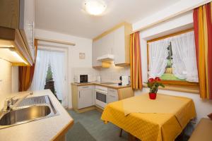 a kitchen with a sink and a table with a yellow table cloth at Pension Alpina Neustift in Neustift im Stubaital