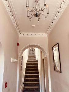 a hallway with a staircase with a chandelier at 'Bloomfield' at stayBOOM in Lancaster