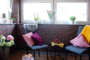 dwa krzesła z kolorowymi poduszkami w pokoju z oknami w obiekcie Gästewohnung Mönchengladbach w mieście Mönchengladbach
