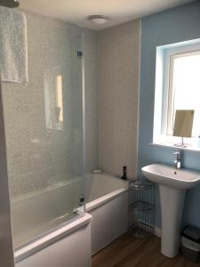 a bathroom with a tub and a sink and a shower at Loch Caroy Bay Cottage in Ose