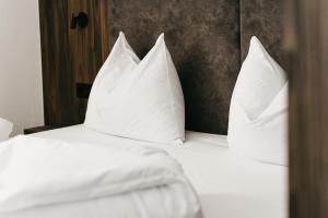 uma cama com almofadas brancas em cima em Nepomuk rooms em Vipiteno
