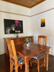 Una mesa de comedor de madera con dos sillas y flores encima. en Foothills B&B, en Maseru