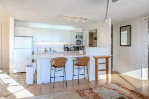 a kitchen with white cabinets and a counter with stools at Mid Century Modern Tropical Getaway 30 plus night rental in Honolulu