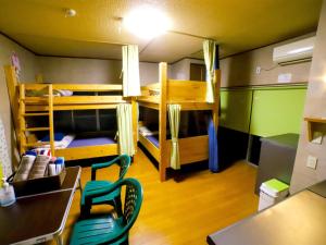 Zimmer mit Etagenbetten, einem Tisch und einem Schreibtisch in der Unterkunft Guesthouse TOKIWA - Vacation STAY 01079v in Fujinomiya
