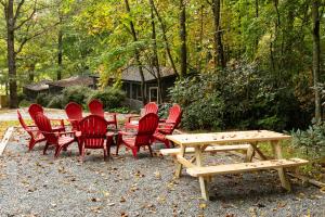 eine Gruppe roter Stühle, ein Holztisch und eine Bank in der Unterkunft Foggy Bottom Cabins in Pisgah Forest