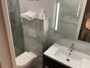 een badkamer met een wastafel, een toilet en een spiegel bij Hôtel Léonard de Vinci II in Parijs