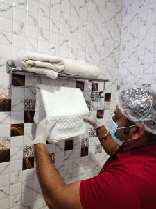 a man in a room with a mask and a shelf with towels at Dwelling Residency in Greater Noida
