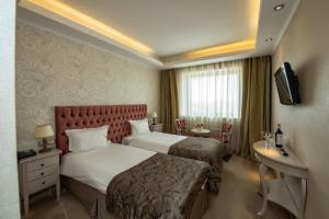 Hotel Roman by Dumbrava Business Resort في رومان: غرفه فندقيه سريرين وتلفزيون