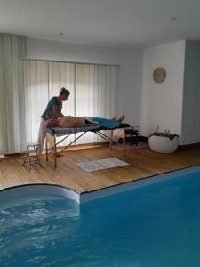 a woman sitting on a bed next to a swimming pool at Auverg'Nature Chambre Auvergnate massage ayurvédique in Espinasse