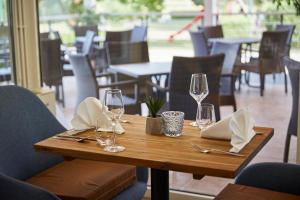 a wooden table with wine glasses and napkins on it at THERMAL RESORT LENDAVA - Terme Lendava, Hotel in Lendava