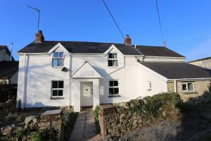 a white house with a stone wall at Ashdale Cottage cosy 4 bedroom holiday home near Amroth in Pembrokeshire