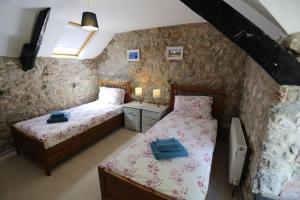 a bedroom with two beds and a stone wall at Ashdale Cottage cosy 4 bedroom holiday home near Amroth in Pembrokeshire
