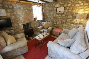 a living room with couches and a stone wall at Ashdale Cottage cosy 4 bedroom holiday home near Amroth in Pembrokeshire