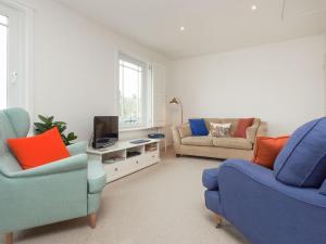 ein Wohnzimmer mit 2 blauen Stühlen und einem TV in der Unterkunft College View 2 Lower in Kingswear