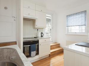 a kitchen with white cabinets and a stove top oven at College View 2 Lower in Kingswear
