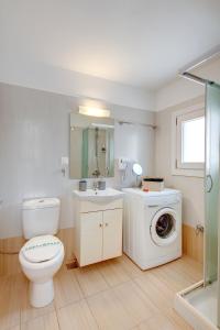 a bathroom with a toilet and a washing machine at Cova Philoxenia House in Ermoupoli
