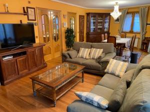 een woonkamer met banken, een televisie en een tafel bij Casa Conchita de Benasque in Benasque