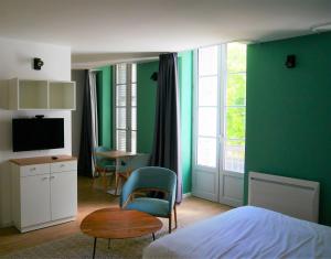 - une chambre avec des murs verts, un lit et une table dans l'établissement Première Pierre, à Verdelais