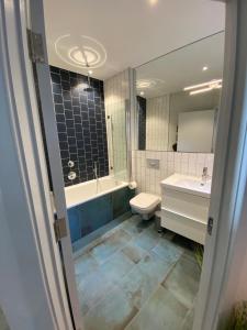 a bathroom with a tub and a toilet and a sink at May Road, stylish townhouse in Twickenham