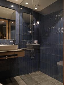 W wyłożonej niebieskimi kafelkami łazience znajduje się umywalka i prysznic. w obiekcie Quality Hotel Match w mieście Jönköping