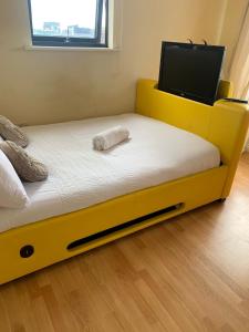 a yellow bed in a room with a flat screen tv at City Centre Penthouse in Southampton