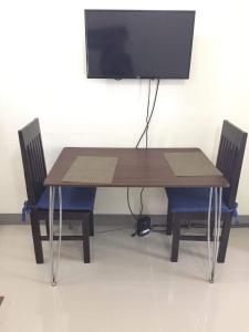 mesa de madera con 2 sillas y TV de pantalla plana. en Kassel residences condo en Manila