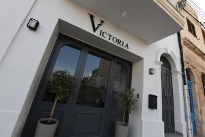 a store front with a black door and two potted plants at Victoria by Petit Chic in Mellieħa