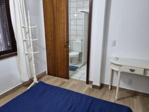 a bathroom with a toilet and a table with a blue rug at Residencial Suites Mariscal in Bombinhas +187 photos