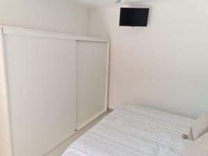 a white bedroom with a bed and a tv on the wall at Apart Esperanza in Esperanza