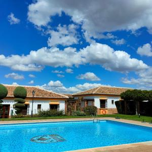a villa with a swimming pool in front of a house at Hotel Rural Carlos Astorga in Archidona