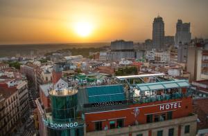 a tour boat on top of a building with the sunset in the background at Hotel Santo Domingo in Madrid